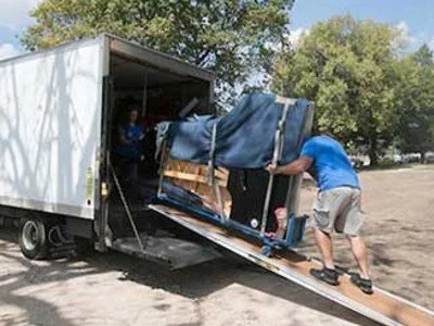 2 removalists moving piano onto truck